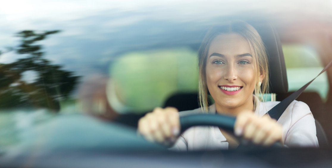 Mujer manejando viendo a través del vidrio del parabrisas.